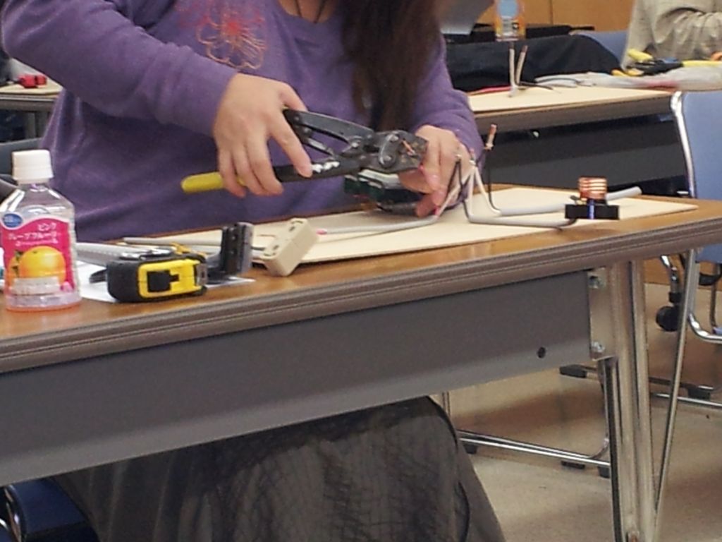女性受講生が圧着工具を使って実技練習に取り組んでいる様子